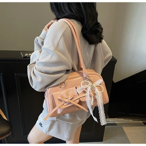Close-up of pink glossy patent leather bag with bow details and pearl lace charm