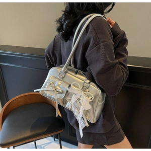 Detail of silver metallic handbag featuring lace trim, pearl pendant and bow accent