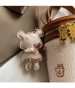 Detail of cylinder bucket bag with contrast stitching and bear-shaped leather charm