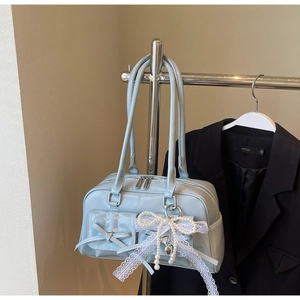 Detail of light blue bowling bag featuring a lace bow pendant and silver zipper hardware