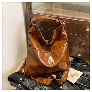 Dettaglio borsa in PU lucido marrone caramello con tasche esterne e fibbie argento