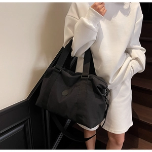 Close-up of a large black travel tote bag with durable handles and adjustable shoulder strap