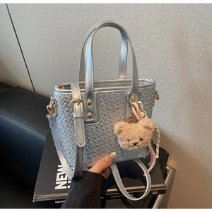Detail of silver woven bucket bag with fashion plaque and brown plush bear charm