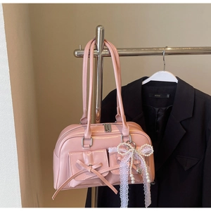 Pink bowling bag detail featuring front flap pockets with bows and a pearl lace charm