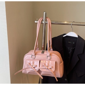 Detail of pink glossy leather bag featuring front bow pockets and silver metal hardware