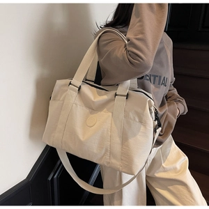 Close-up of beige waterproof nylon travel tote with reinforced handles and crossbody strap