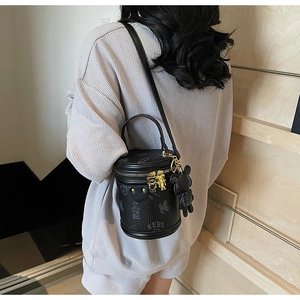 Close-up of black cylinder bag with golden bear zippers and a hanging bear charm