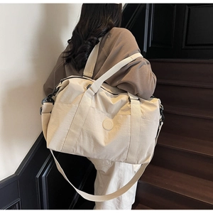 Detail view of large capacity beige travel tote with adjustable shoulder strap and handles