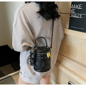 Detail of black cylindrical bucket bag with bear print and bear-shaped zipper charm