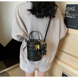 Fashionable cylinder bucket bag in black leather with bear charms and metal details