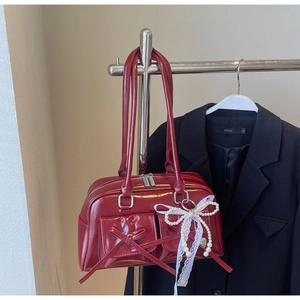Detail of burgundy patent leather bowling bag with lace bow and metal heart pendant