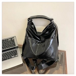 Dettaglio della grande borsa tote in pelle verniciata nera lucida su una scrivania di vetro