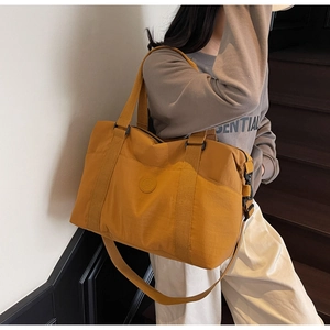 Detail of mustard yellow travel tote bag featuring adjustable strap and circular logo