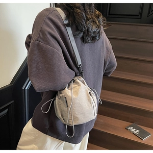 Detail der beigen Nylon-Umhängetasche mit Kordelzug und Netztasche am Model