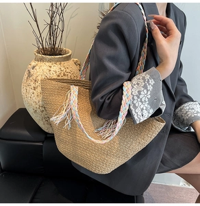 Dettaglio della borsa tote in paglia con tracolle intrecciate colorate e nappe decorative