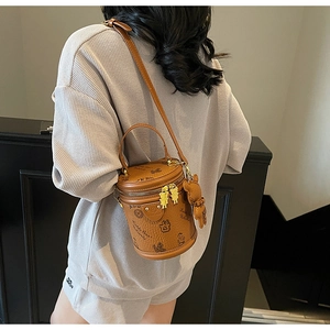 Detail of a brown cylinder bucket bag with teddy bear print and cute bear charms