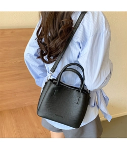 Vista posteriore di una modella con borsa a secchiello nera motivo litchi e tracolla fine