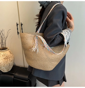 Dettaglio della borsa tote in paglia intrecciata a mano con tracolle colorate e nappe