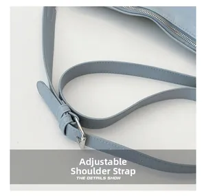 Detail of light blue leather dumpling bag featuring silver buckle and adjustable strap