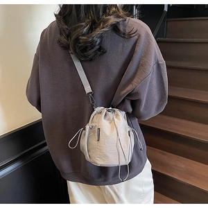 Detail der grauen Nylon-Beuteltasche mit Kordelzug und Netzseitentasche am Modell getragen