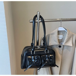 Detail of black glossy bowling bag with bow pockets hanging on a metal rack
