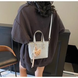 Silver woven bucket bag with cute bear charm shown as a crossbody on a female model