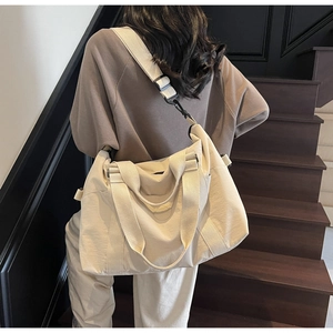 Woman carrying large beige canvas travel tote bag with adjustable strap on stairs