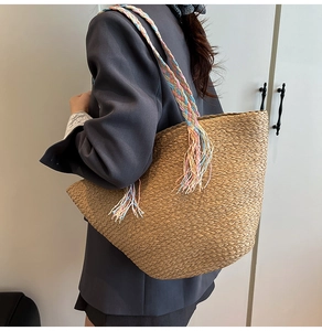 Dettaglio della grande borsa tote in paglia con tracolla a nappe colorate e trama intrecciata