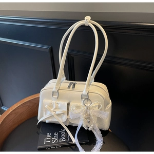 Detailed view of cream-white glossy shoulder bag with front pockets and lace pearl charm