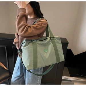 Detail of light green travel tote bag with adjustable shoulder strap and top handles