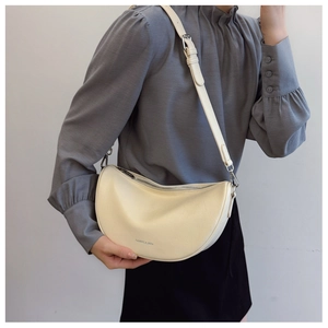 Close-up of cream crescent bag featuring lychee grain leather and adjustable shoulder strap