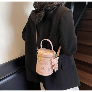 Detail of pink cylinder bucket bag with embossed texture and cute bear charm pendant