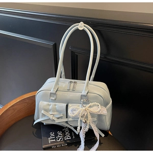 Detail of light blue patent leather bag featuring double front pockets and lace bow charm