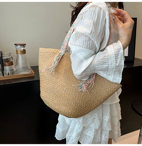 Dettaglio borsa tote in paglia intrecciata con tracolla arcobaleno su abito in pizzo