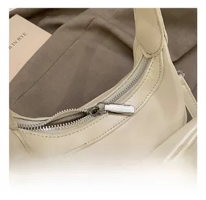 Detailed view of cream faux leather handbag with metal zipper and triangular plaque