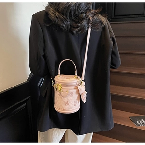 Detail of pink cylinder bucket bag with embossed textures and a cute bear keychain