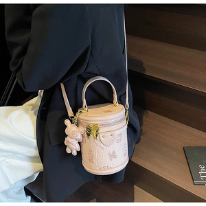 Detail of pink cylinder bucket bag showing pebbled leather texture and bear pendant