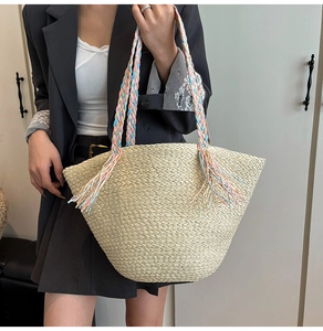Dettaglio borsa tote in paglia di carta intrecciata con manici colorati e nappe decorative