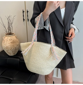 Dettaglio borsa tote in paglia beige intrecciata con manici in corda colorata e nappe