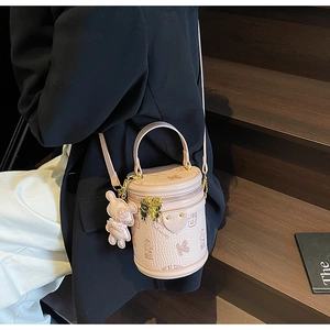 Pink cylinder bucket bag with lychee texture, bear pendant and dual metal zippers