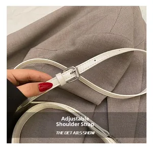 Detail of adjustable white leather shoulder strap with silver buckle on a stylish handbag