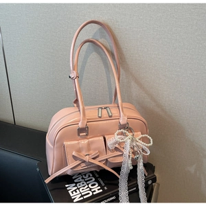Close-up of pink patent leather bag featuring bow details and a pearl heart charm