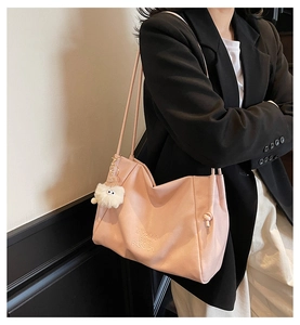 Pink PU leather tote bag detail with embossed lettering and plush monster charm accessory