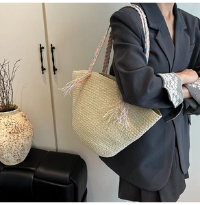 Dettaglio della borsa tote in paglia intrecciata con tracolle in nastro colorato