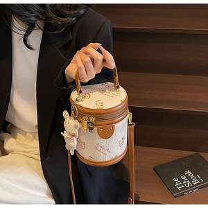 Detail of white cylinder bucket bag with teddy bear prints and bunny charm on stairs