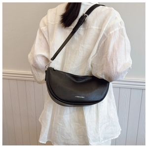 Detail of black leather half-moon bag with lychee texture and adjustable strap