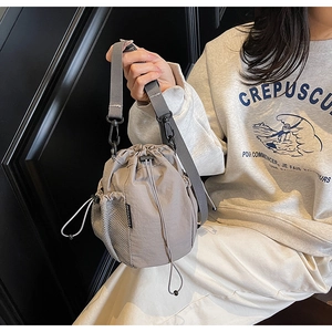 Details der hellgrauen Nylon-Beuteltasche mit Netztasche und breitem Schultergurt