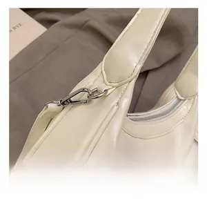 Close-up of premium metal hook attachment and neat stitching on off-white handbag