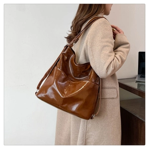 Dettaglio borsa a tracolla vintage in pelle marrone lucida con tracolla regolabile e tasca