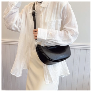 Detail of adjustable strap and silver metal buckle on a black textured leather bag